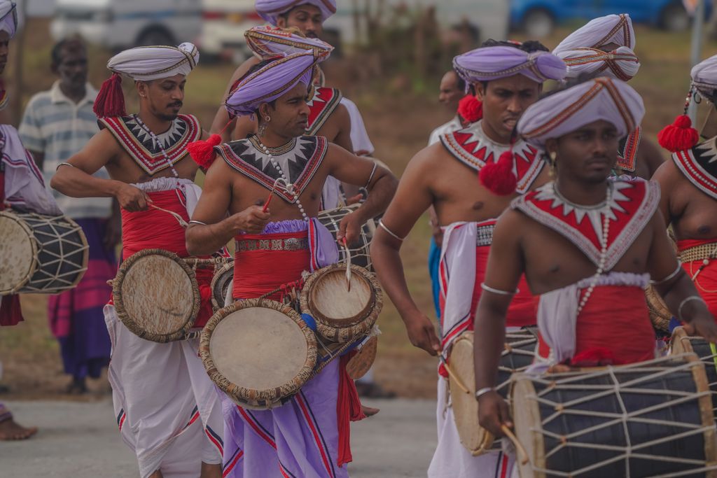 Sri Lankan drummers in traditional attire performing in a vibrant cultural parade.